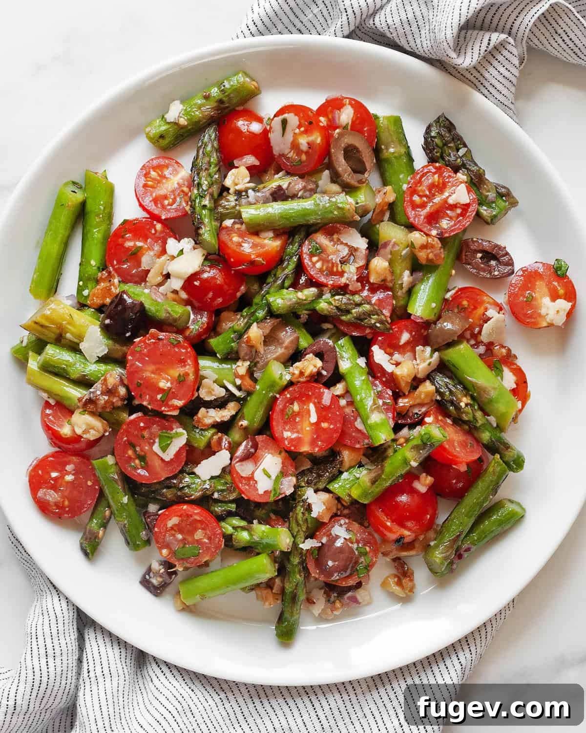 Mediterranean Grilled Asparagus Medley 7 A serving of grilled asparagus tomato salad on a white plate, garnished with fresh herbs.