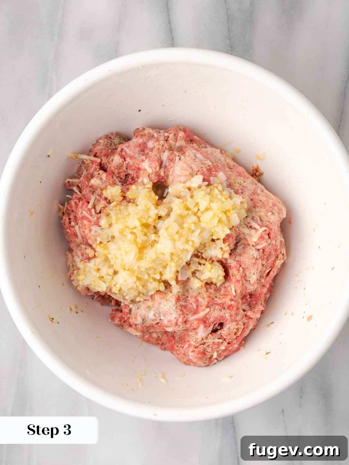 Cloud-Like Ricotta Meatballs 7 Meatball mixture with sautéed garlic and onion added on top, ready for final mixing to combine flavors.