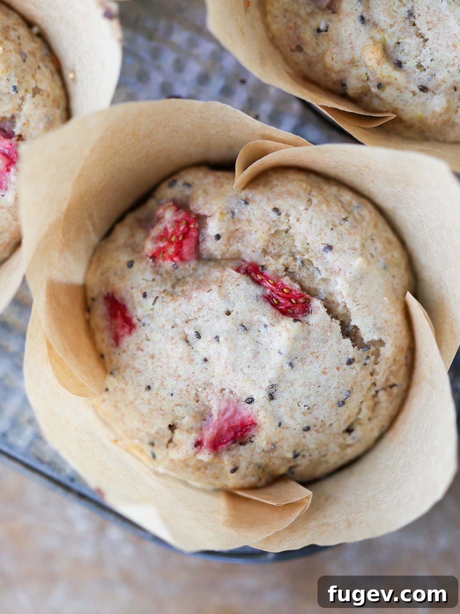Homemade Strawberry Muffins 2 A freshly baked Whole Wheat Strawberry Muffin in a vintage baking tin, showcasing its golden-brown top and visible strawberry pieces.