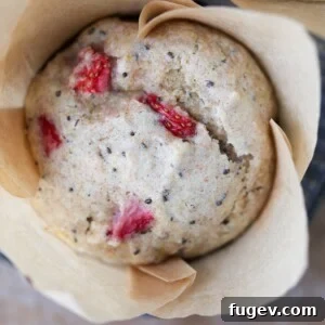 A beautiful strawberry whole wheat muffin in a brown tulip liner, perfectly baked and ready to be enjoyed.