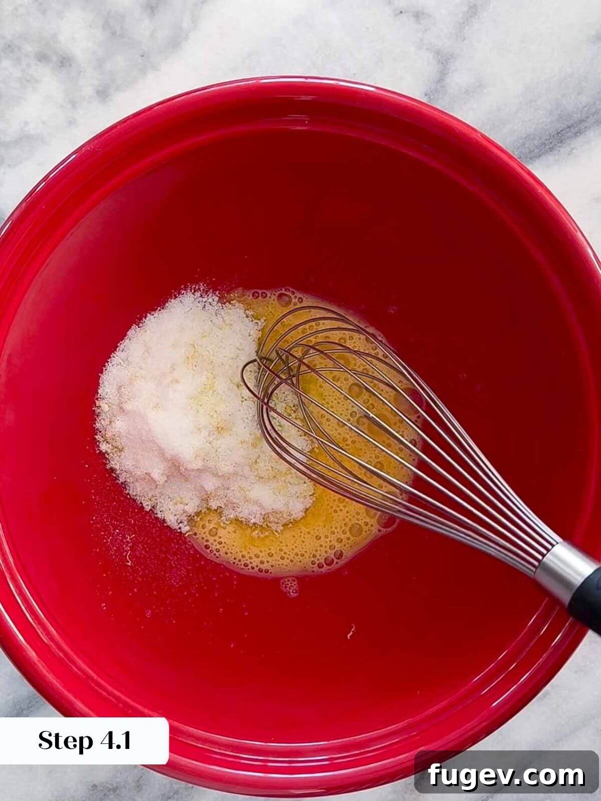 Homemade Strawberry Muffins 5 A hand adding granulated sugar to a bowl with fresh lemon zest and lemon juice, part of the wet ingredients preparation for the muffins.