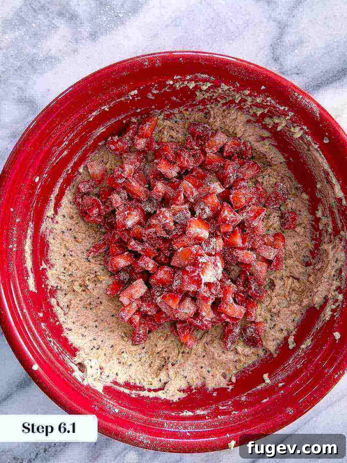 Homemade Strawberry Muffins 8 Chopped fresh strawberries being added to the prepared muffin batter in a large mixing bowl.