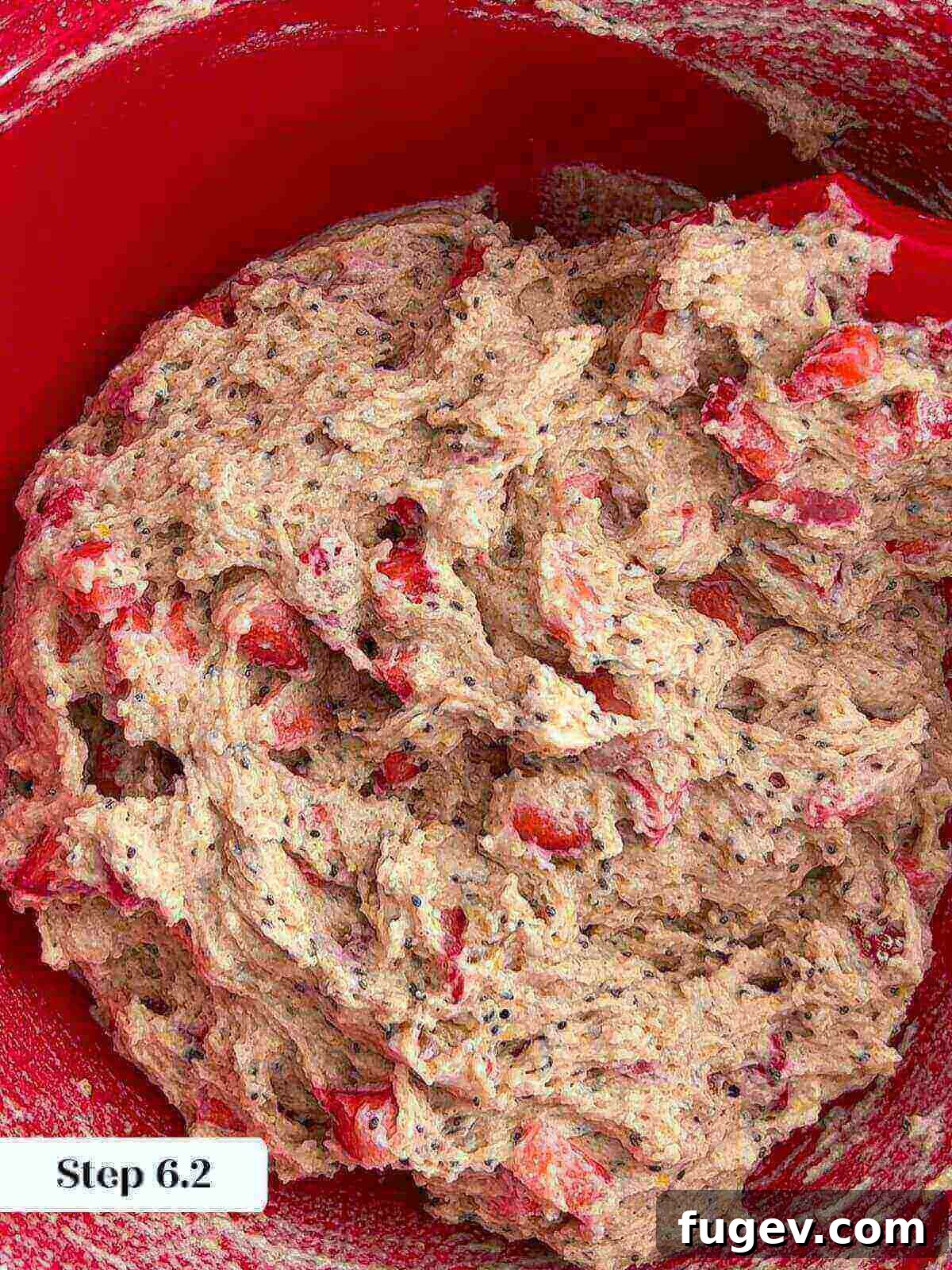Homemade Strawberry Muffins 9 A rubber spatula gently folding fresh strawberries into the muffin batter, ensuring even distribution without overmixing.
