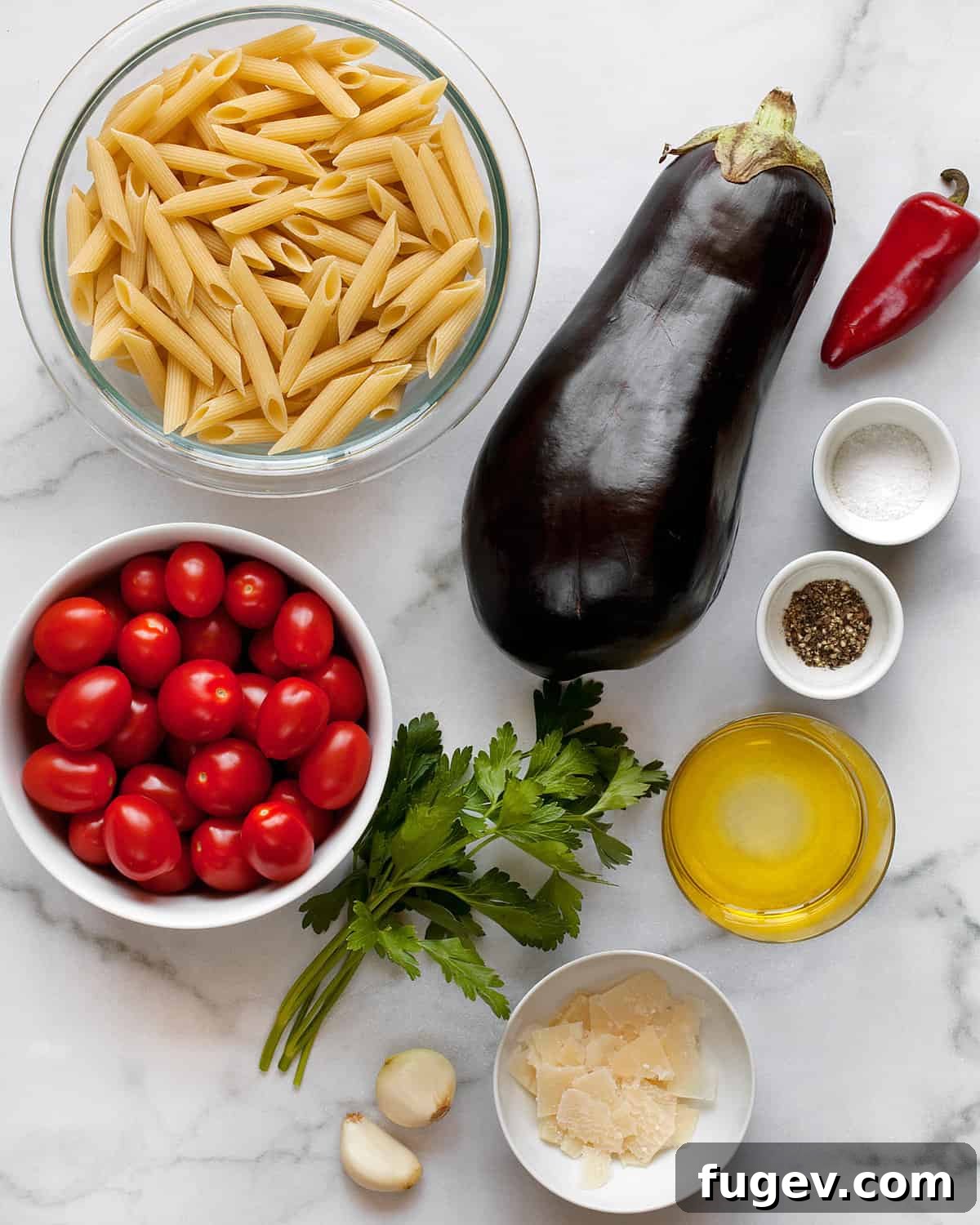 Roasted Eggplant and Burst Cherry Tomato Pasta 3 A vibrant flat lay image showcasing the fresh ingredients required for cherry tomato eggplant pasta: penne, diced eggplant, whole and halved cherry tomatoes, Fresno chili, garlic cloves, fresh parsley, olive oil, and seasonings.