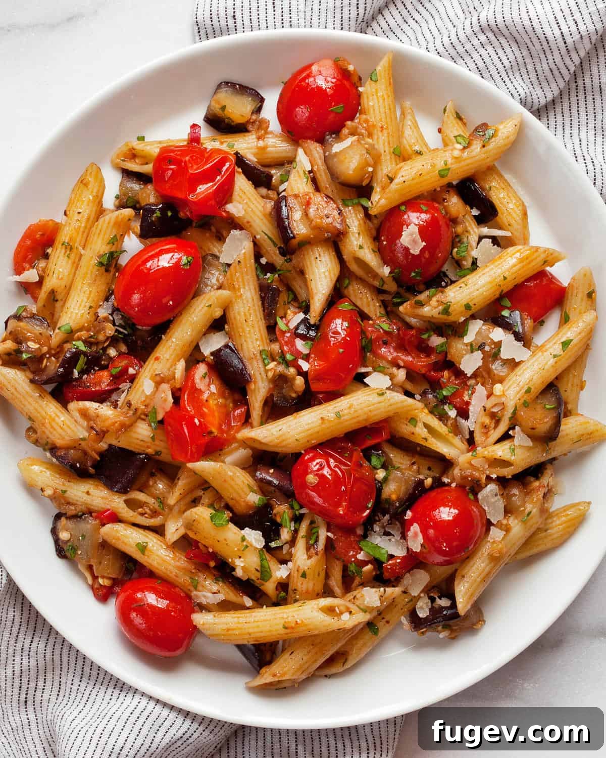 Roasted Eggplant and Burst Cherry Tomato Pasta 8 A vibrant close-up of cherry tomato eggplant pasta served on a white plate, ready to be enjoyed.