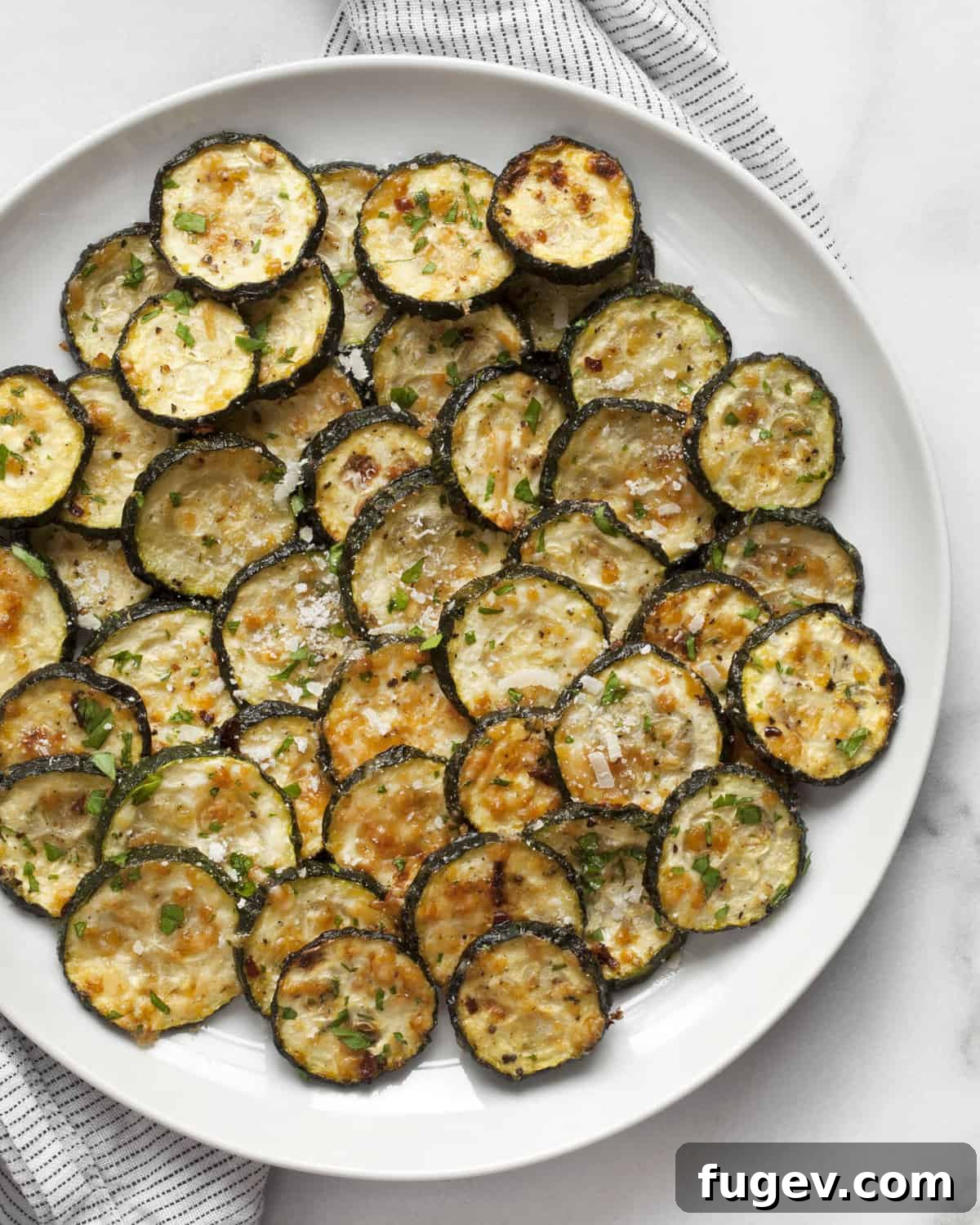 Golden Parmesan Zucchini 2 Perfectly roasted zucchini slices with grated Parmesan and fresh parsley on a serving plate.