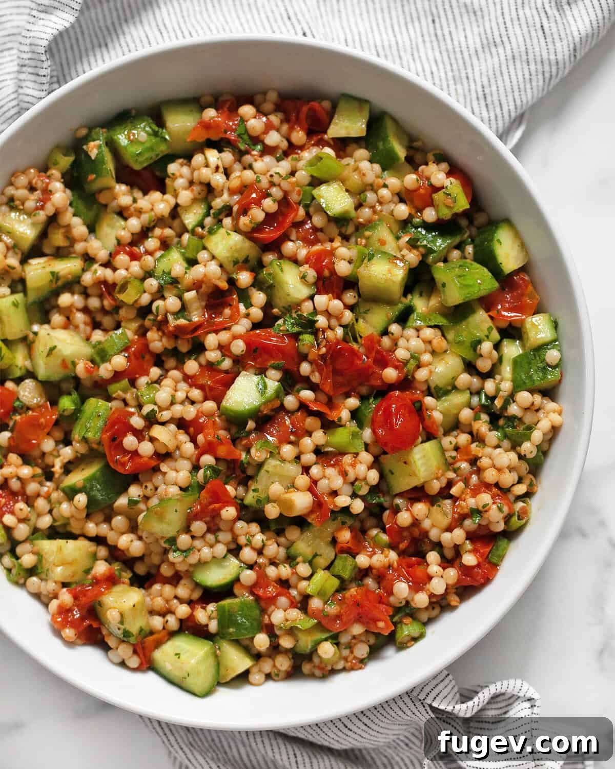 Spicy Harissa Roasted Tomato Couscous 2 A vibrant bowl of Harissa Roasted Tomato Couscous, showcasing the rich colors of roasted tomatoes, green herbs, and golden couscous.