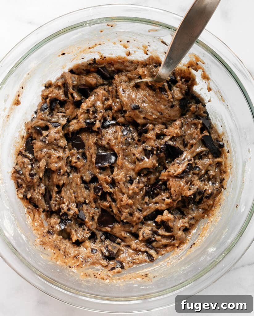 Cinnamon-Kissed Vegan Chocolate Chip Cookies 7 Stirring the vegan cookie dough in a bowl, showcasing its glossy texture before chilling