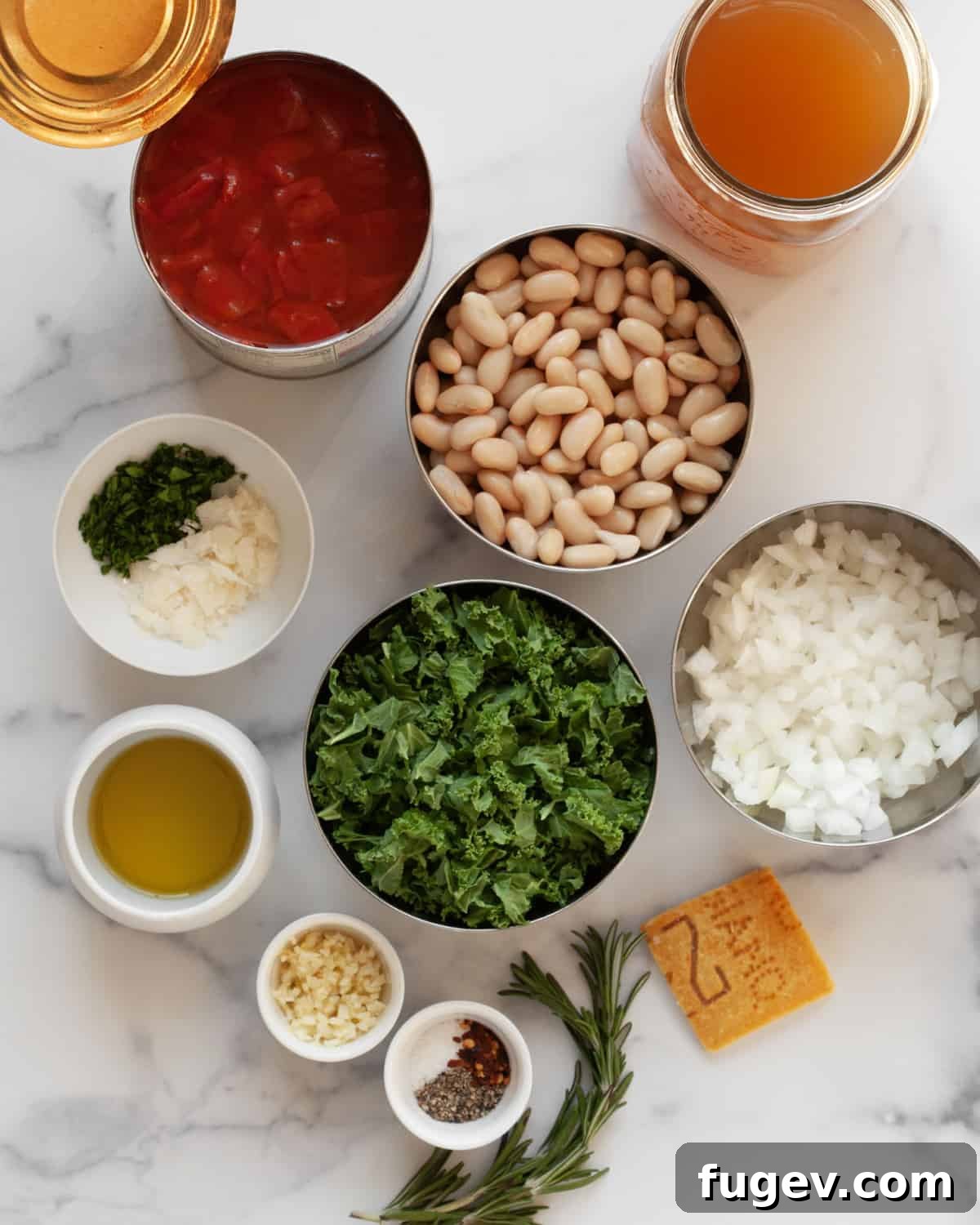 Rustic Rosemary White Bean Tomato Soup 3 A vibrant display of fresh ingredients for rosemary white bean tomato soup, including ripe tomatoes, fresh rosemary sprigs, cannellini beans, kale, vegetable broth, garlic cloves, a parmesan rind, and seasoning.