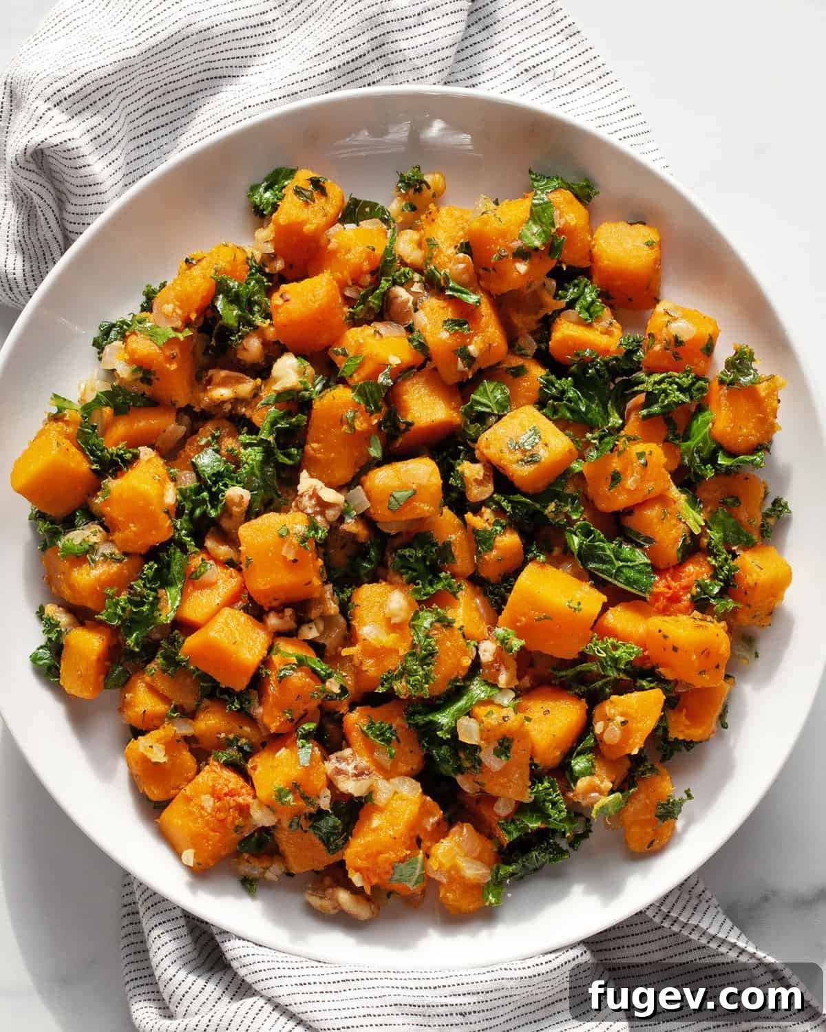 Roasted Autumn Squash Medley 2 Sautéed kale and butternut squash on a plate, garnished with fresh parsley and toasted walnuts.
