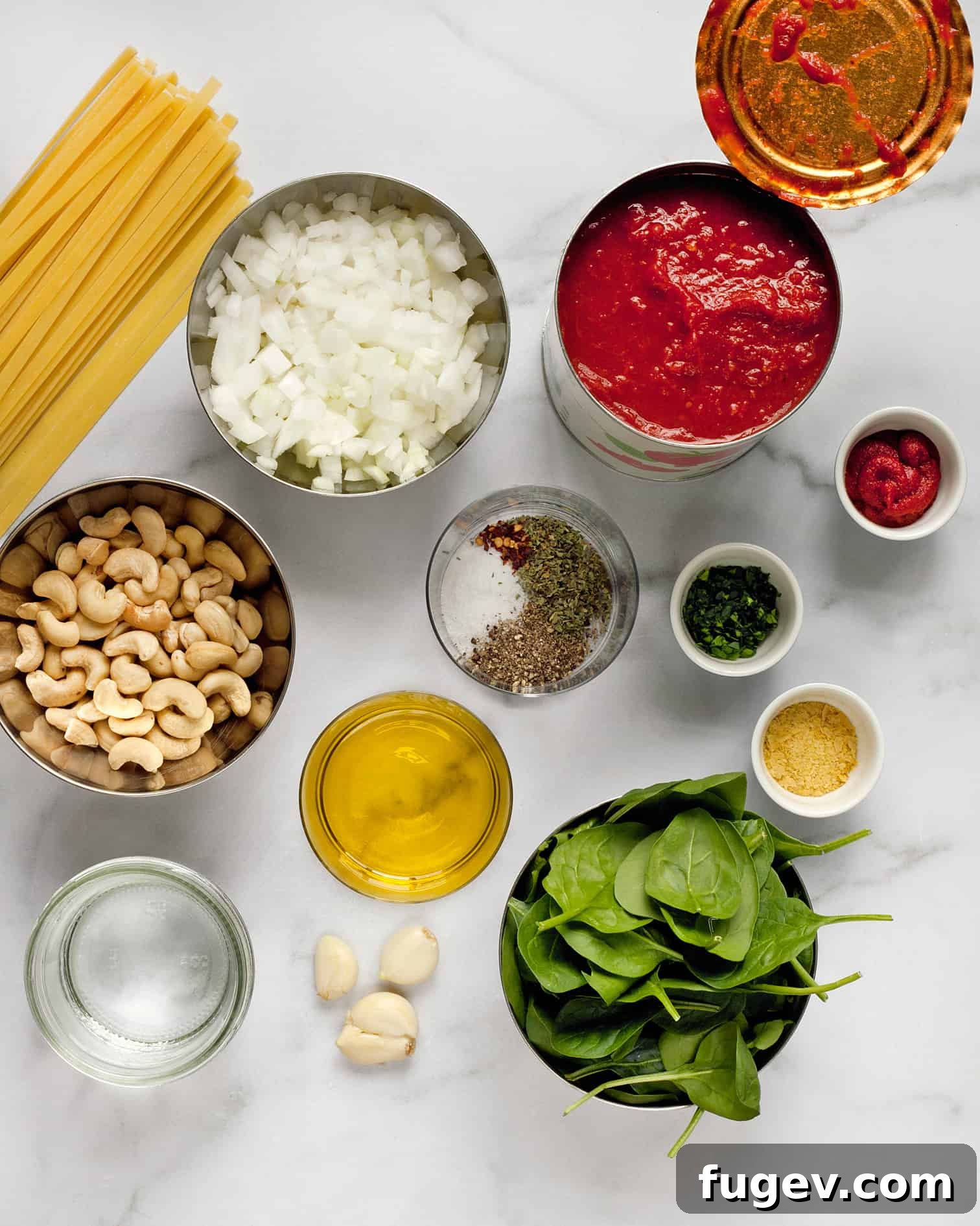Velvety Vegan Tomato Spinach Pasta 4 Ingredients for vegan pasta including tomatoes, spinach, garlic, olive oil, and cashews, laid out on a table