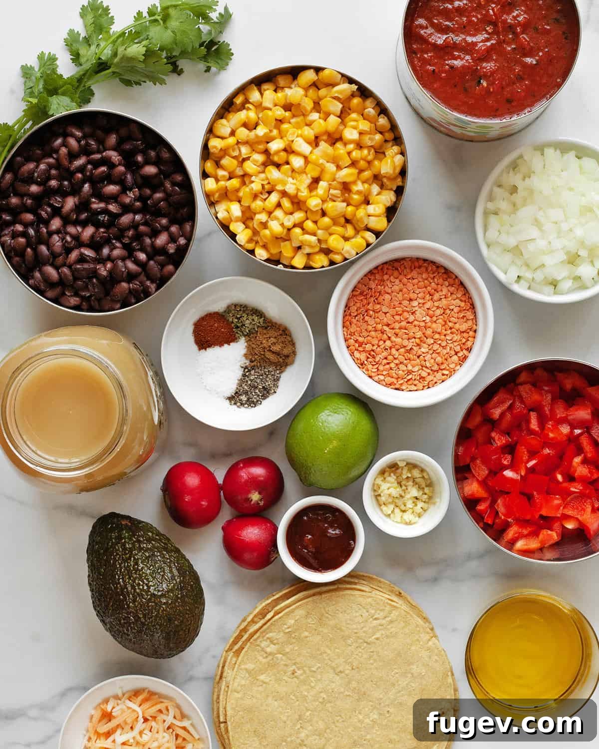 Plant-Based Slow Cooker Tortilla Soup 3 A collection of fresh and canned ingredients for slow cooker lentil tortilla soup, including black beans, corn, tomatoes, red lentils, vegetable broth, onions, spices, garlic, adobo sauce, and corn tortillas.