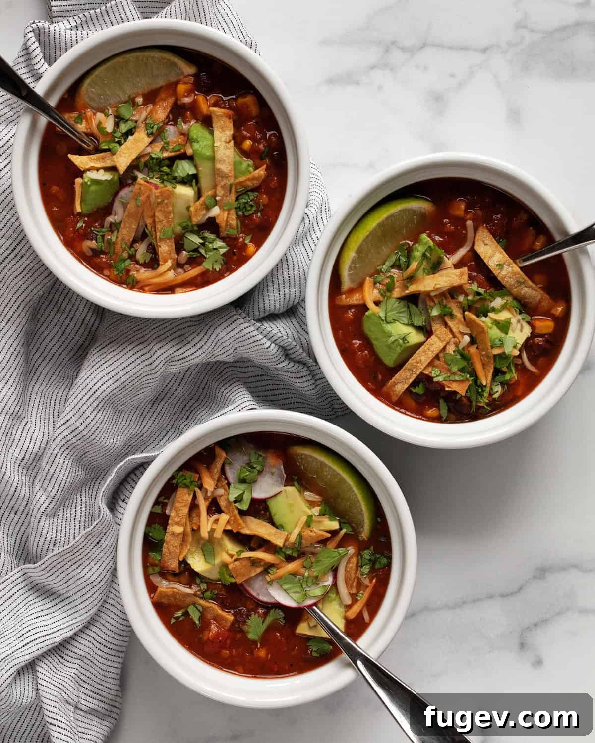 Plant-Based Slow Cooker Tortilla Soup 8 Three beautifully arranged bowls of hearty tortilla soup, garnished with various fresh toppings and crispy tortilla strips, ready to be enjoyed.