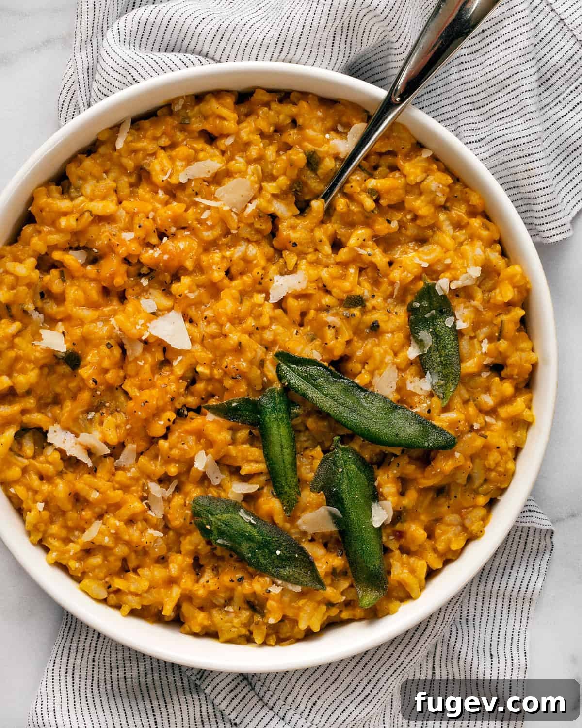 Velvet Pumpkin Risotto 3 A large serving spoon scooping creamy baked pumpkin risotto from a rustic bowl, highlighting its rich texture.