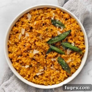 Baked pumpkin risotto in a serving bowl garnished with sage and Parmesan.