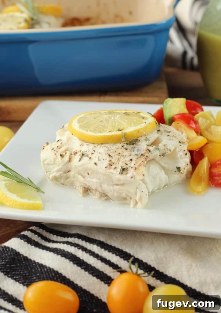 Baked Halibut with Effervescent Champagne Vinaigrette 2 Perfectly Baked Halibut fillet with a golden-brown crust, garnished with fresh lemon slices and rosemary, ready to be served.