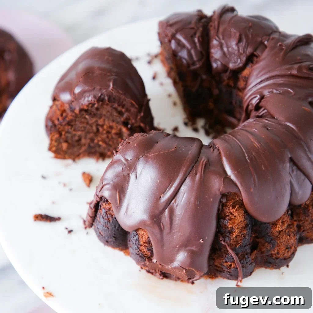 Decadent Fudge Drizzle 3 Chocolate Fudge Glaze coating a slice of chocolate zucchini cake, highlighting its rich color and smooth texture.