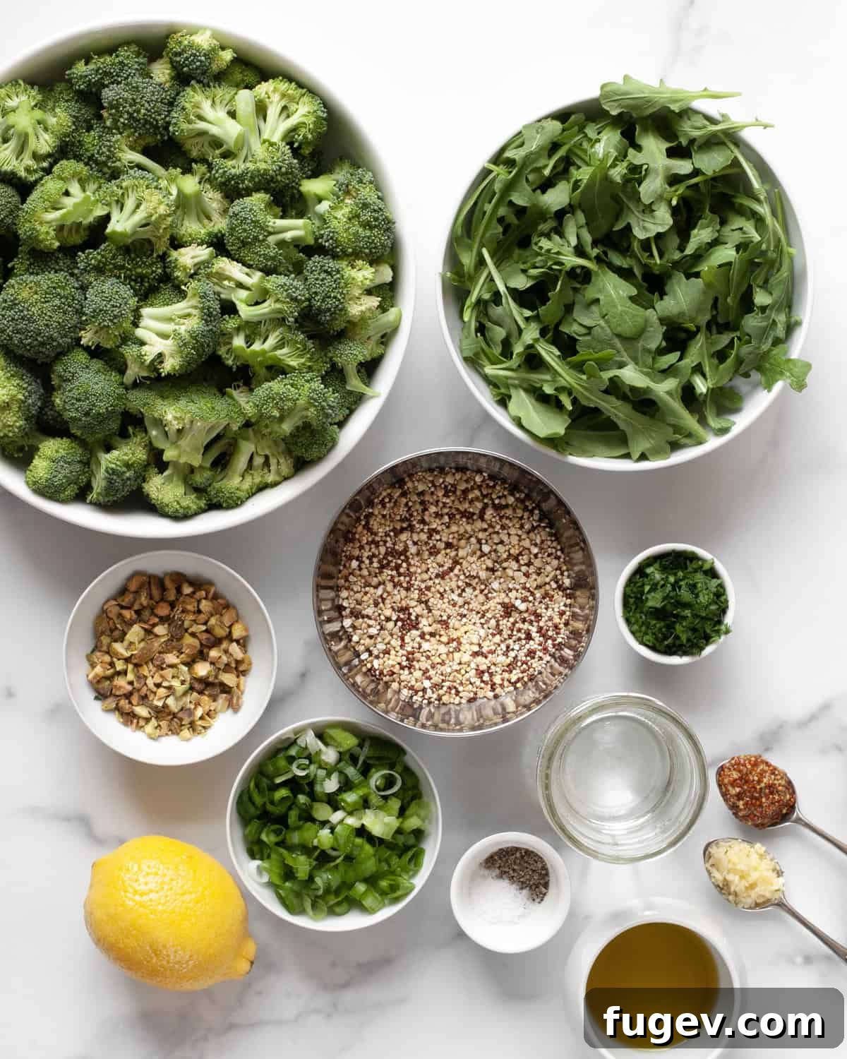 Vibrant Roasted Broccoli Quinoa Salad 3 A flat lay of fresh ingredients for the roasted broccoli quinoa salad, including broccoli florets, quinoa, a bowl of arugula, lemon, pistachios, parsley, garlic, mustard, olive oil, and sliced scallions.