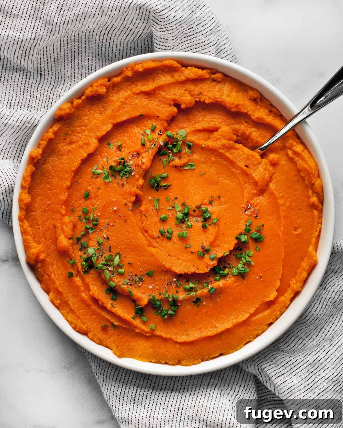 Nourishing Sweet Potato Mash 2 A serving bowl of fluffy, healthy mashed sweet potatoes garnished with fresh herbs, ready to be enjoyed.