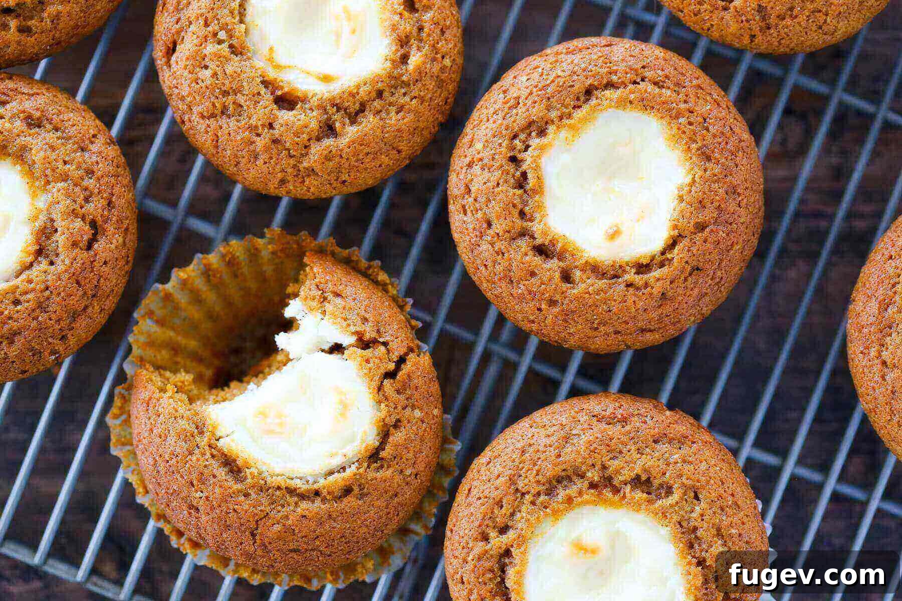 Swirled Pumpkin Cream Cheese Muffins 4 Freshly baked pumpkin muffins with creamy cream cheese filling, cooling on a wire rack.