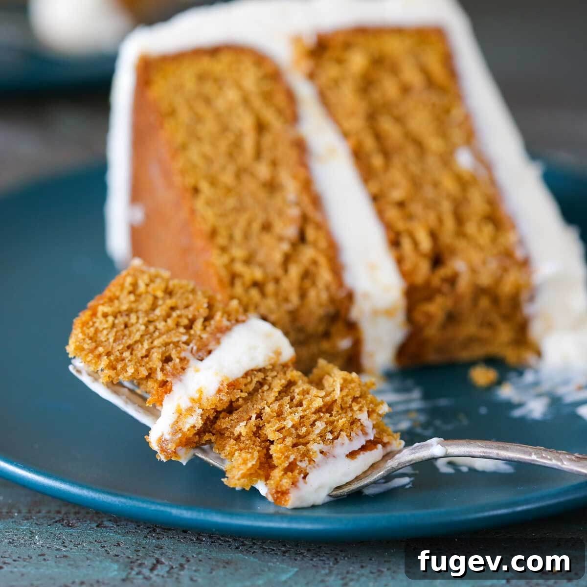 Pumpkin Spice Dream Cake 3 A piece of pumpkin cake on a blue plate, showing its moist texture and cream cheese frosting.