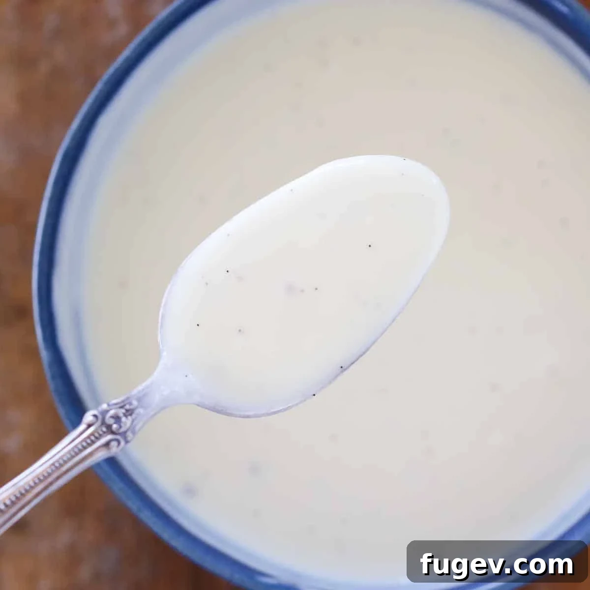 Elegant Vanilla Custard Drizzle 2 creme anglaise on spoon over bowl.
