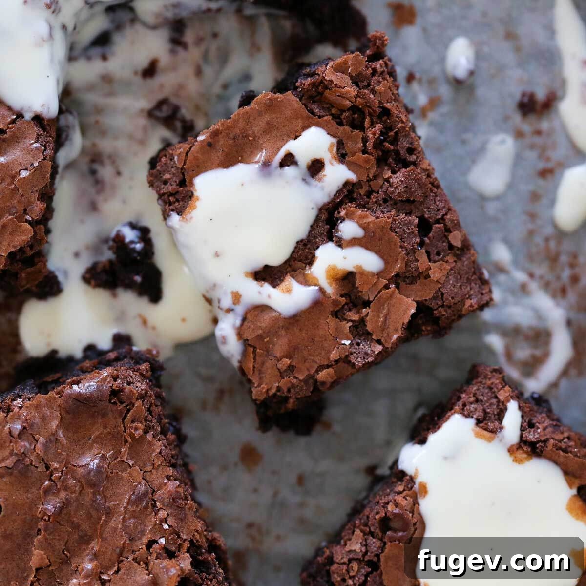 Elegant Vanilla Custard Drizzle 3 brownies on parchment with anglaise on top.