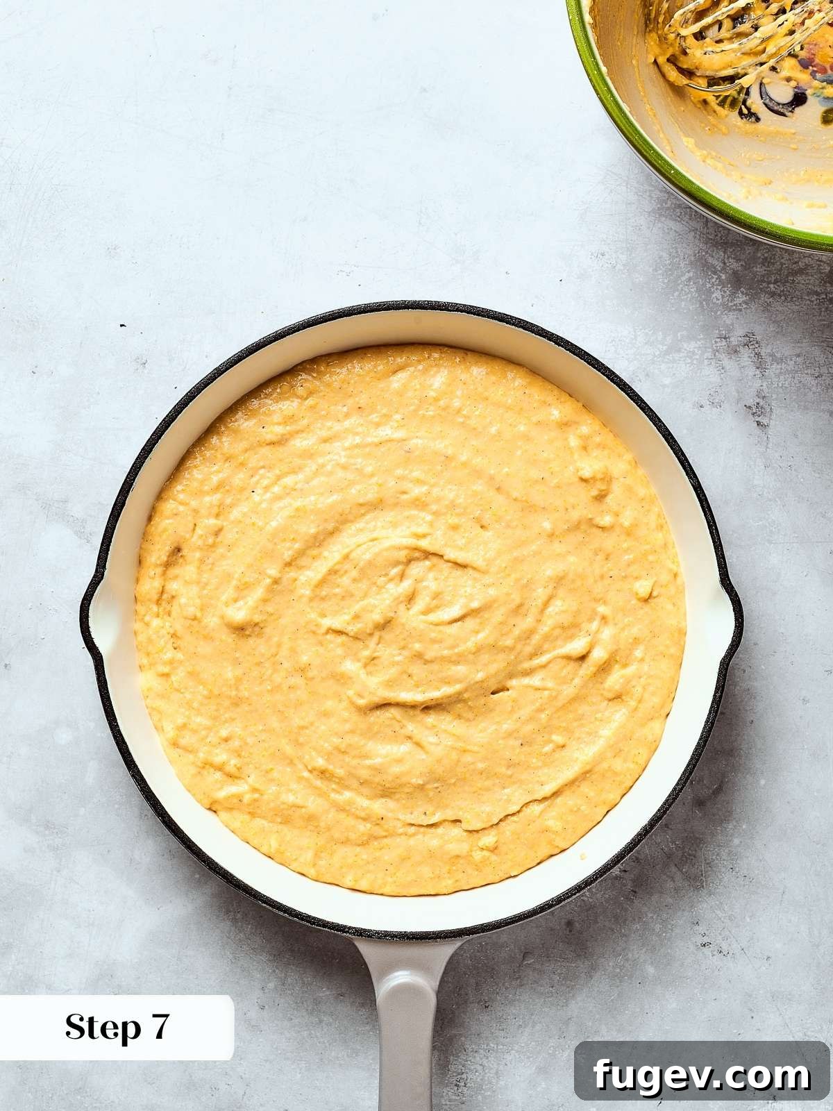 Southern Cornbread Perfection 12 Smooth cornbread batter evenly spread in a hot cast iron skillet, ready for baking to achieve a golden crust.