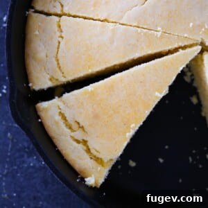 Sliced Southern cornbread resting in a black cast iron skillet, golden top and moist interior clearly visible.