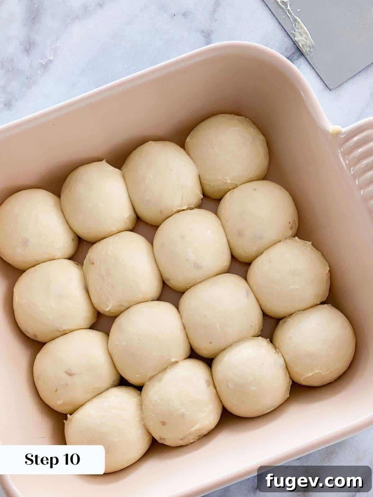 Pillowy Potato Rolls 4 Unproofed potato dough rolls neatly arranged in a baking dish before they begin to rise.