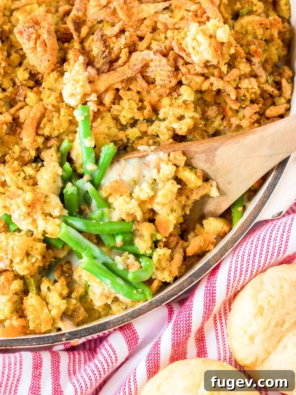 Classic Thanksgiving Dinner Recipes and Full Menu 9 Creamy green bean casserole in a baking dish with a serving spoon, topped with crispy onions.