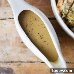 Overhead shot of rich gravy in a white gravy boat, highlighting its smooth texture.