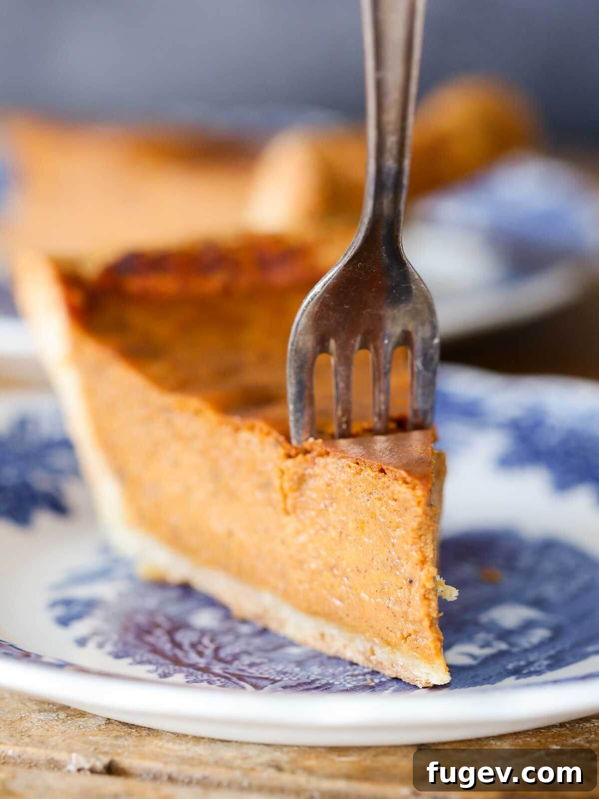 Classic Thanksgiving Dinner Recipes and Full Menu 18 A slice of creamy pumpkin pie with a fork, ready to be enjoyed.