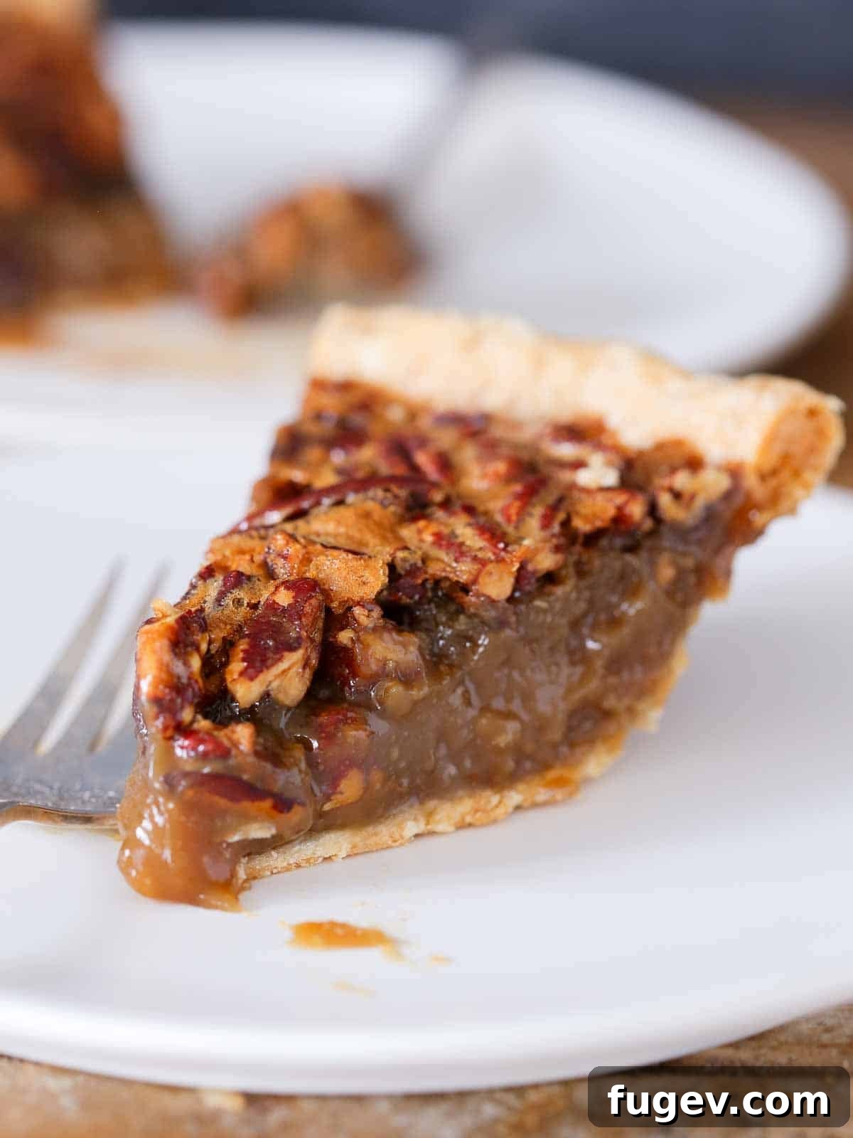 Classic Thanksgiving Dinner Recipes and Full Menu 22 A decadent slice of pecan pie on a white plate, showcasing its rich filling and nutty topping.