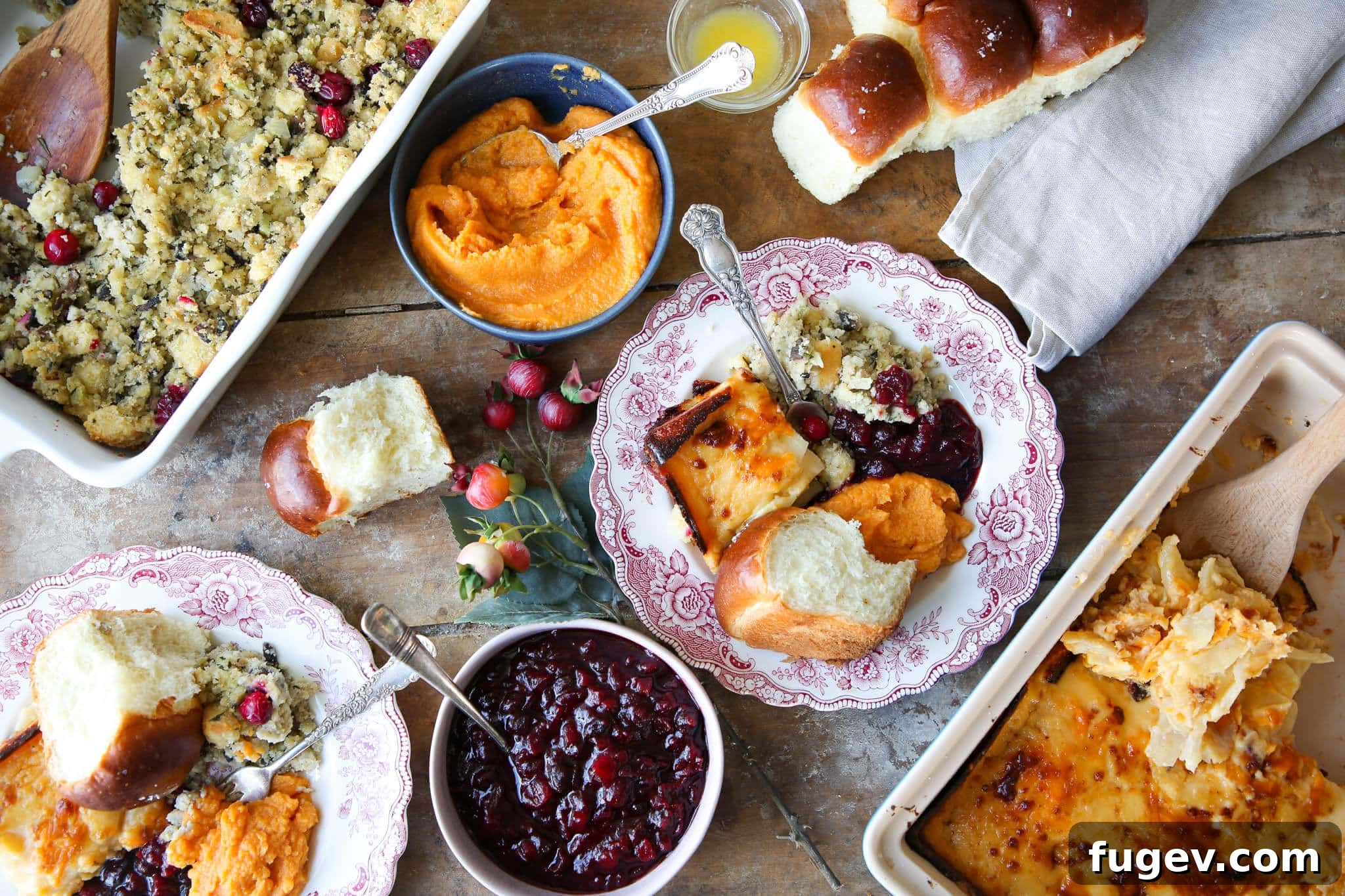Classic Thanksgiving Dinner Recipes and Full Menu 27 Thanksgiving Menu with various plated side dishes and cutlery on a wooden table.
