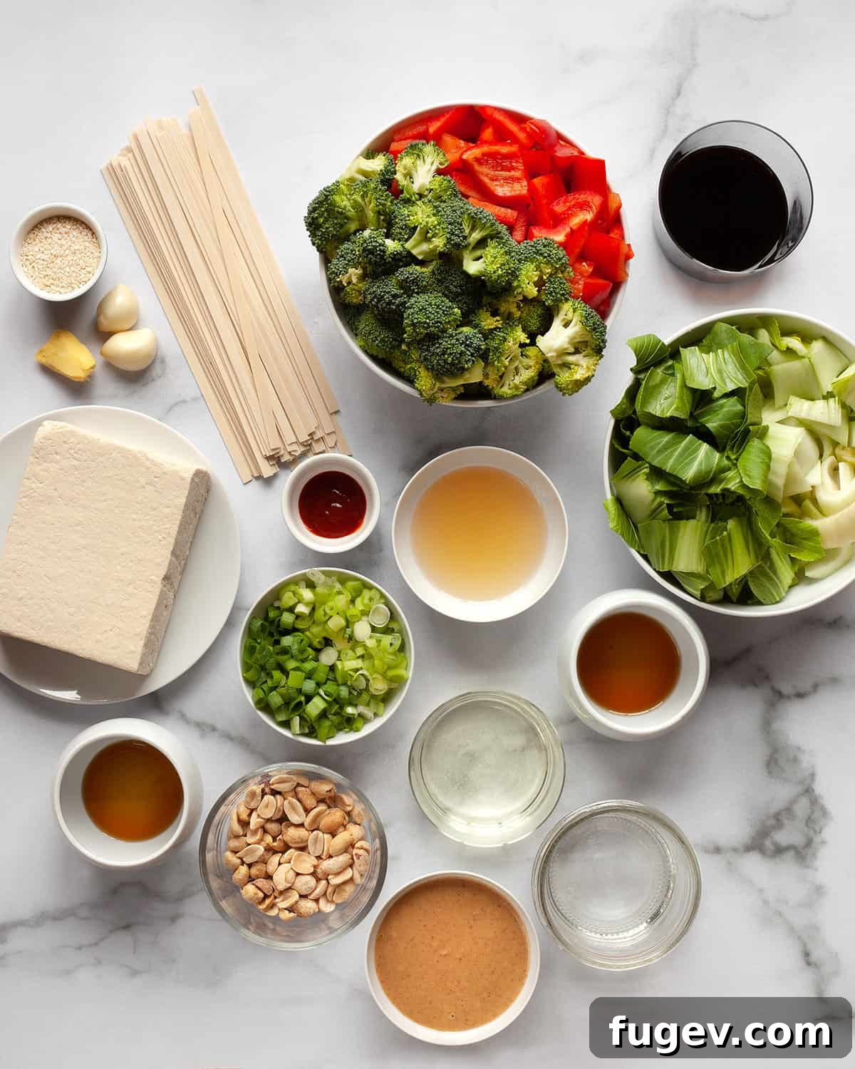 Creamy Peanut Tofu Veggie Stir-Fry 3 Assortment of fresh ingredients including vegetables, peanuts, peanut butter, ginger, noodles, soy sauce, and garlic, ready for cooking.