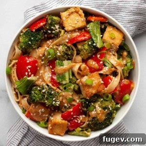 Tofu vegetable stir-fry drizzled with peanut sauce in a bowl.