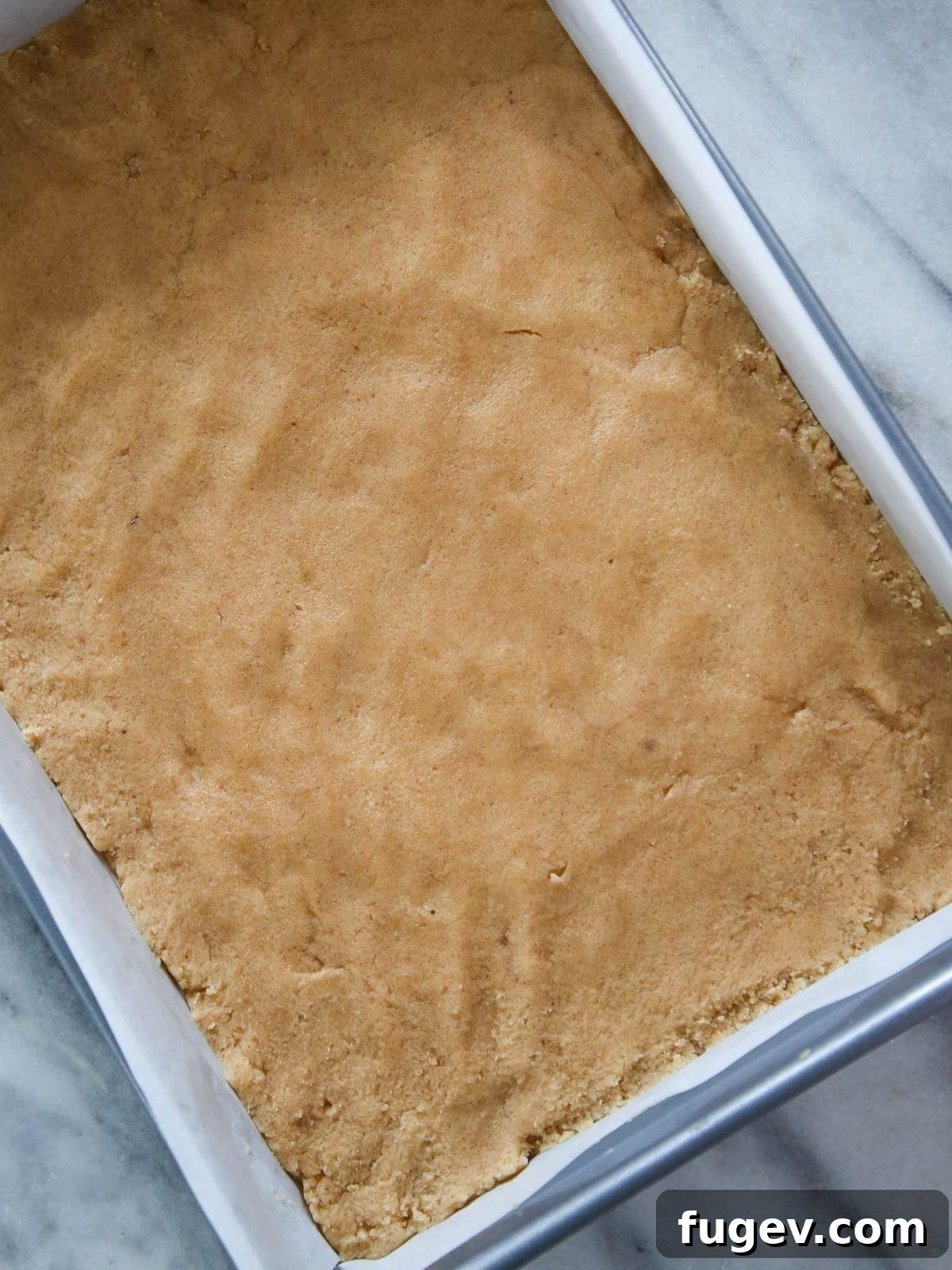 Golden Almond Squares 5 Cookie batter pressed into a silver pan.
