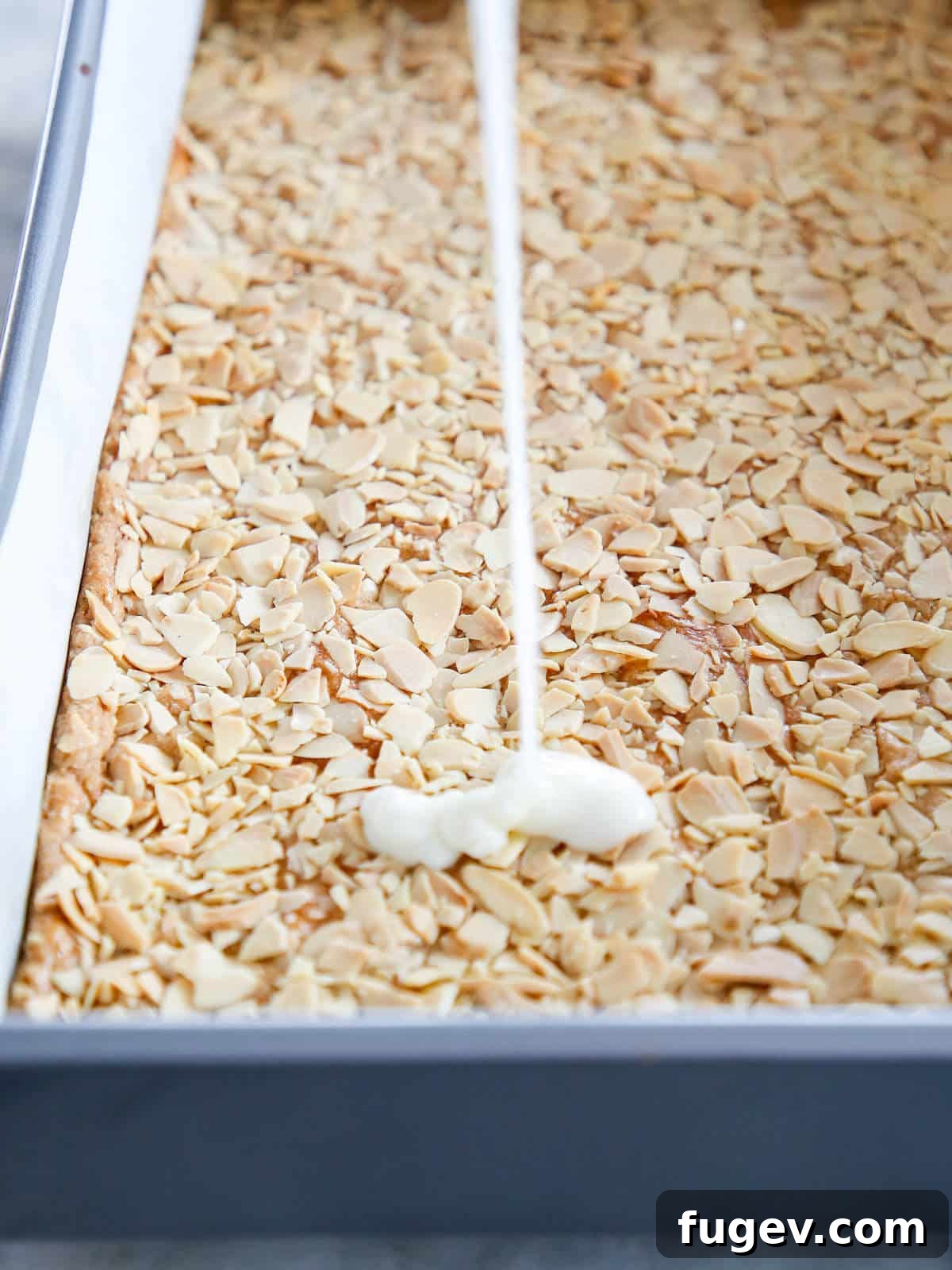 Golden Almond Squares 7 White glaze pouring down onto almond topping.