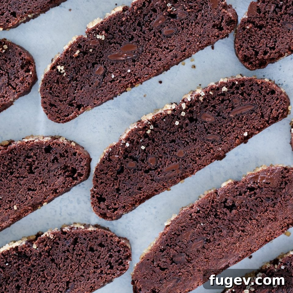 Decadent Chocolate Biscotti 3 Sliced chocolate biscotti arranged neatly on a parchment-lined baking sheet, showcasing their rich color and crunchy texture.