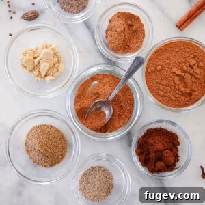 Speculoos Spice Mix on a marble counter, surrounded by measuring spoons and small spice bowls, signifying its preparation.