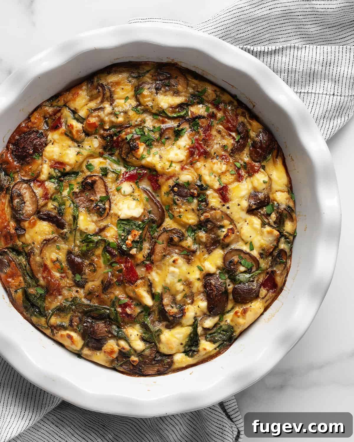 Savory Mushroom, Pepper, and Spinach Frittata 2 A beautifully baked crustless quiche, golden brown on top, filled with visible mushrooms, peppers, spinach, and feta, ready to be sliced.