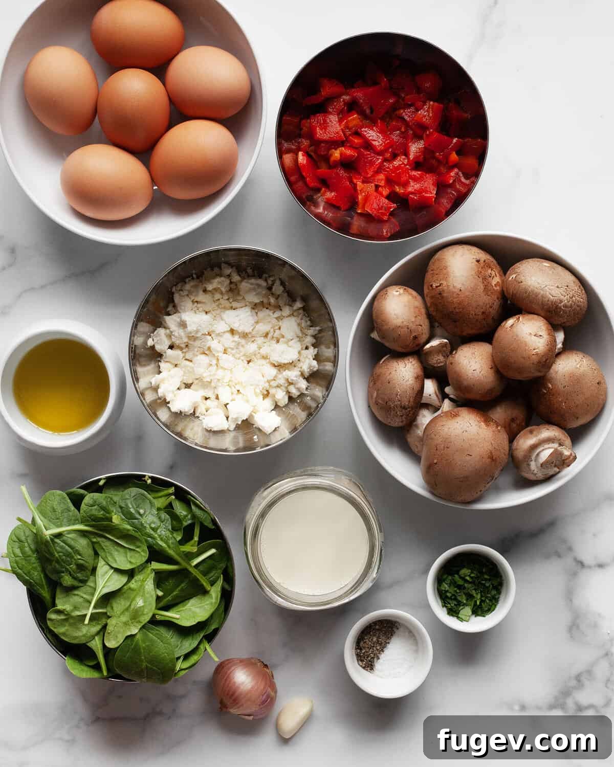 Savory Mushroom, Pepper, and Spinach Frittata 3 Fresh ingredients laid out on a table: eggs, milk, sliced cremini mushrooms, jarred roasted red peppers, crumbled feta, chopped shallots, minced garlic, fresh spinach, olive oil, salt, and pepper.