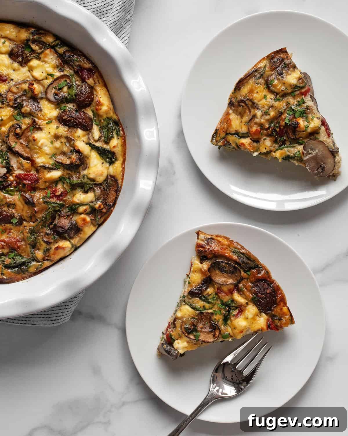 Savory Mushroom, Pepper, and Spinach Frittata 8 Two perfectly cut slices of crustless quiche, revealing layers of mushrooms, red peppers, spinach, and feta, presented on a white plate.