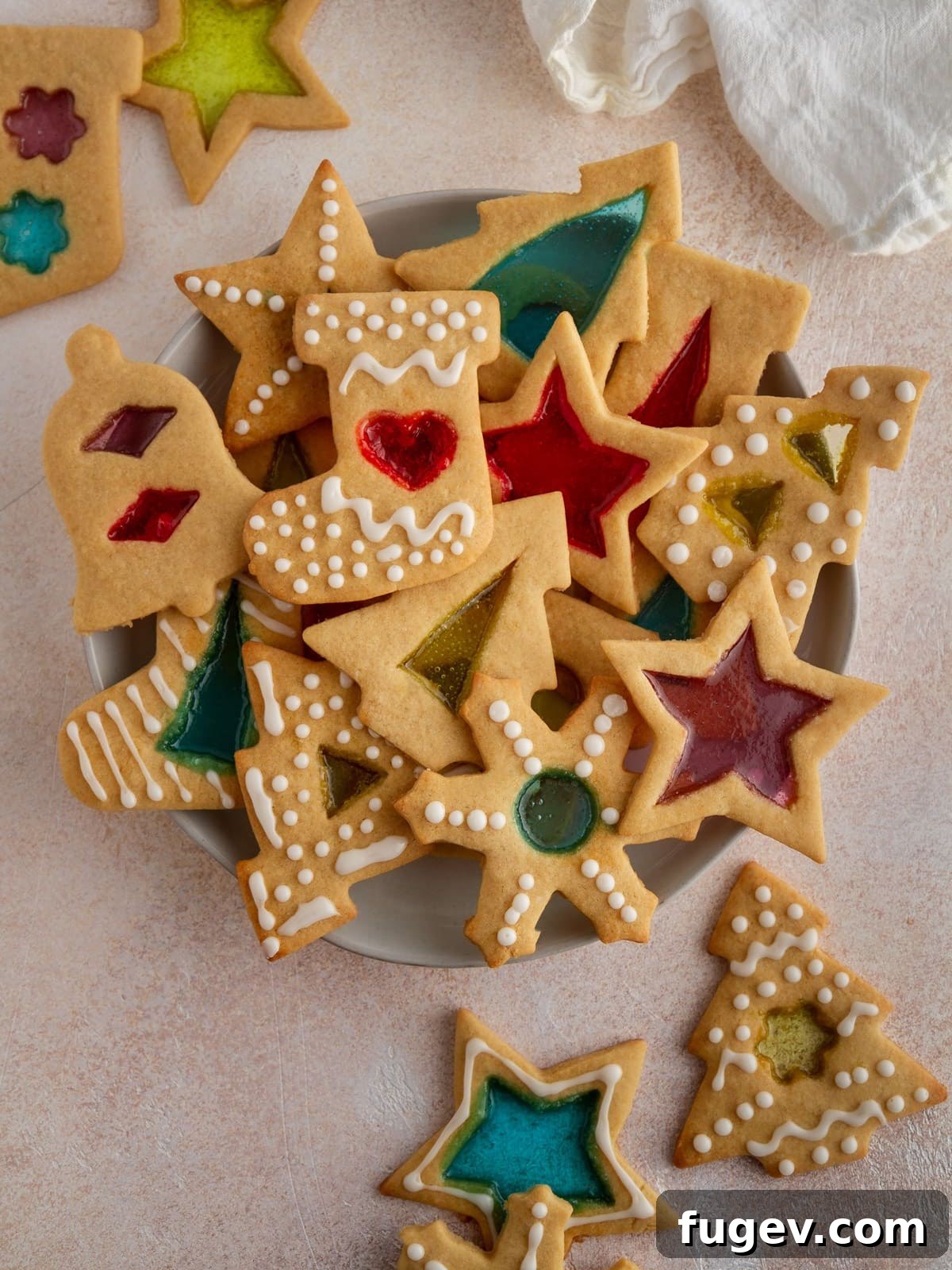 20 Festive Christmas Cookie Recipes 18 stained glass window cookies stacked on plate on pink background.