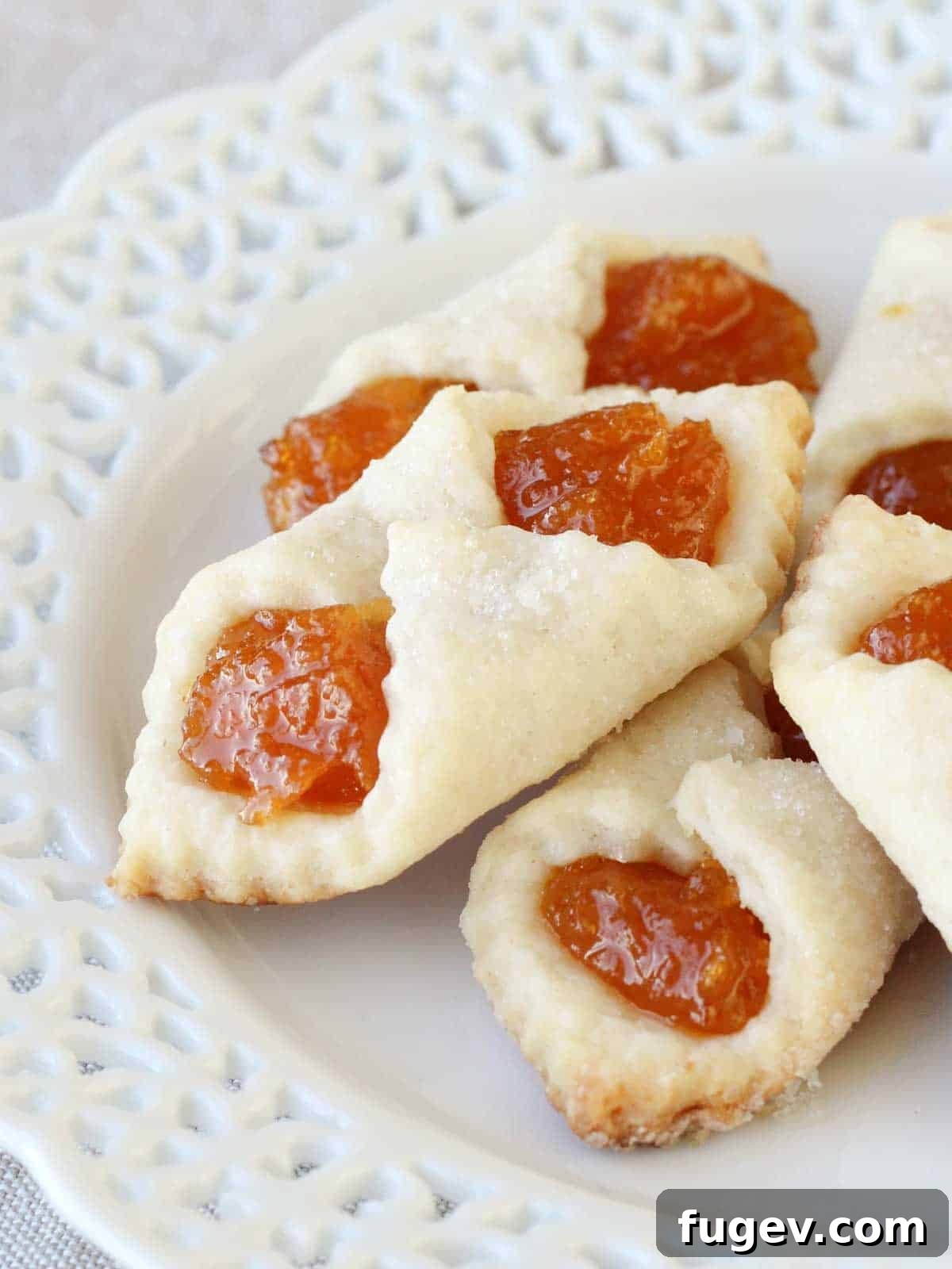 20 Festive Christmas Cookie Recipes 30 apricot kolacky cookies stacked on white lace plate.
