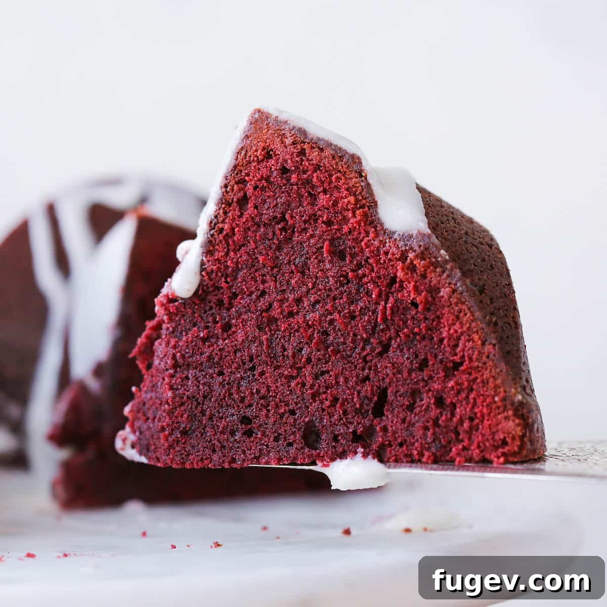 Ultimate Red Velvet Loaf Cake 3 Red Velvet Pound Cake with cream cheese glaze on a cake server, ready to be served.
