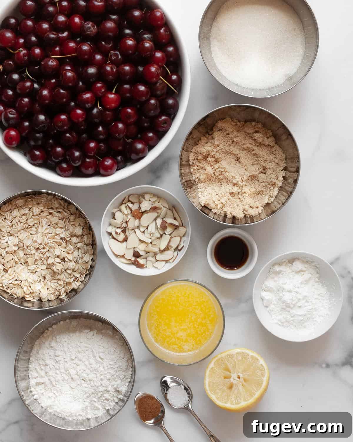 Quick Delicious Cherry Crumble 3 Various ingredients for cherry crumble including fresh cherries, granulated sugar, brown sugar, oats, flour, sliced almonds, lemon, melted butter, vanilla extract, cinnamon, and cornstarch laid out on a surface.