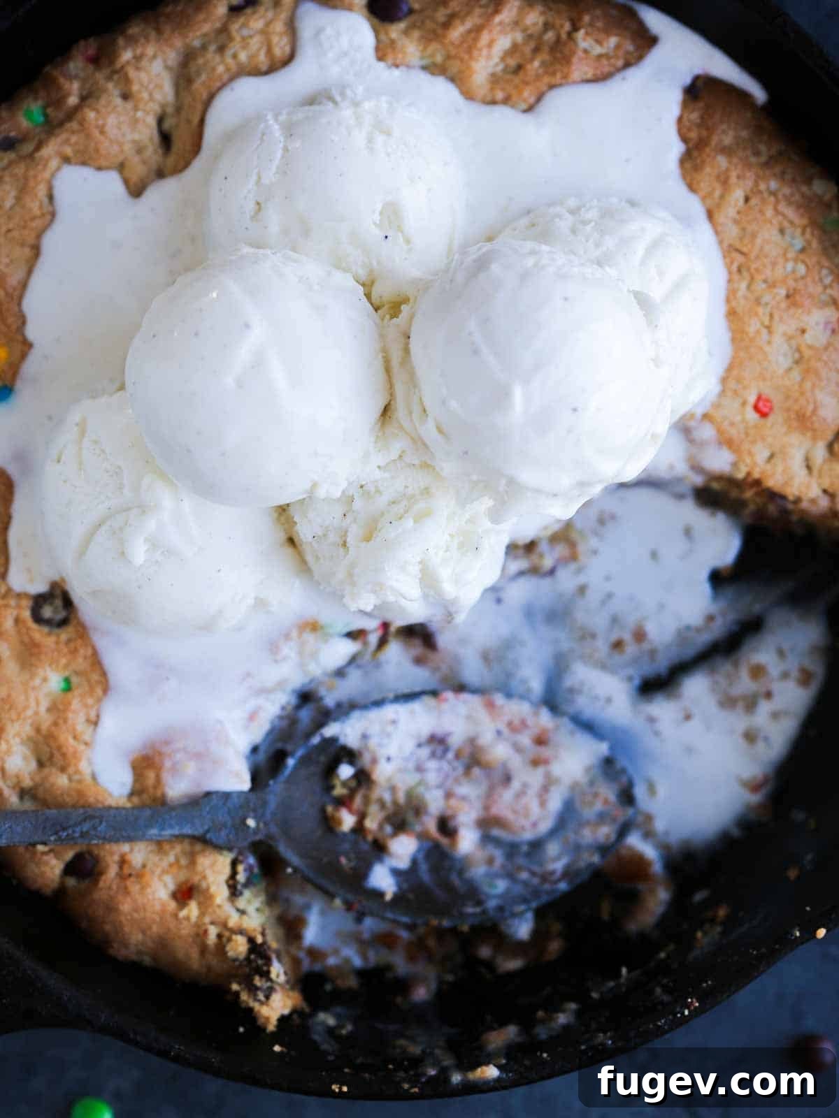 Deep Dish Cookie 2 Warm pizookie baked in a cast iron skillet, topped with melting vanilla bean ice cream.