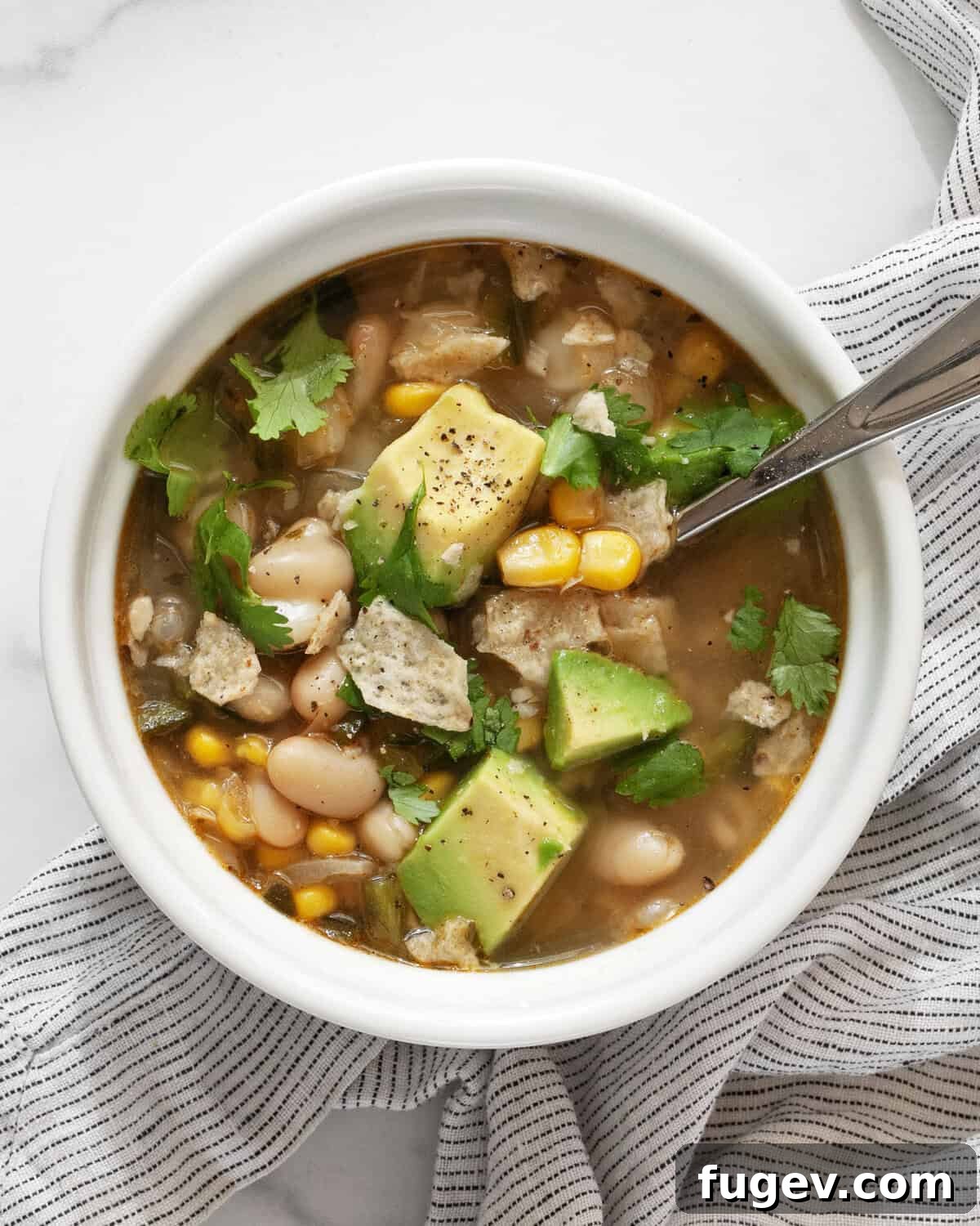 Creamy Vegan Poblano White Bean Chili 2 A single, inviting bowl of hearty vegan white bean chili, garnished with fresh avocado and cilantro.